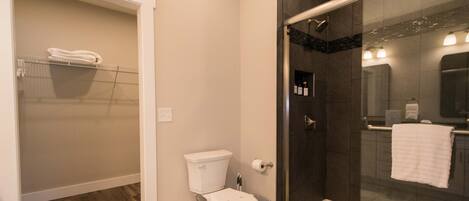 A bathroom with a toilet, a glass shower enclosure, and a towel rack.