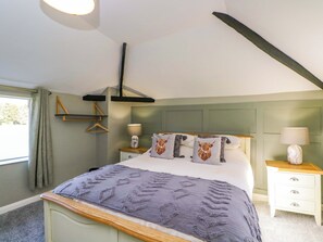 A bedroom with a bed, bedside tables, a hanging light fixture, a window with curtains, and a wall-mounted shelf. - 3 Woods Farm House (Chippenham)