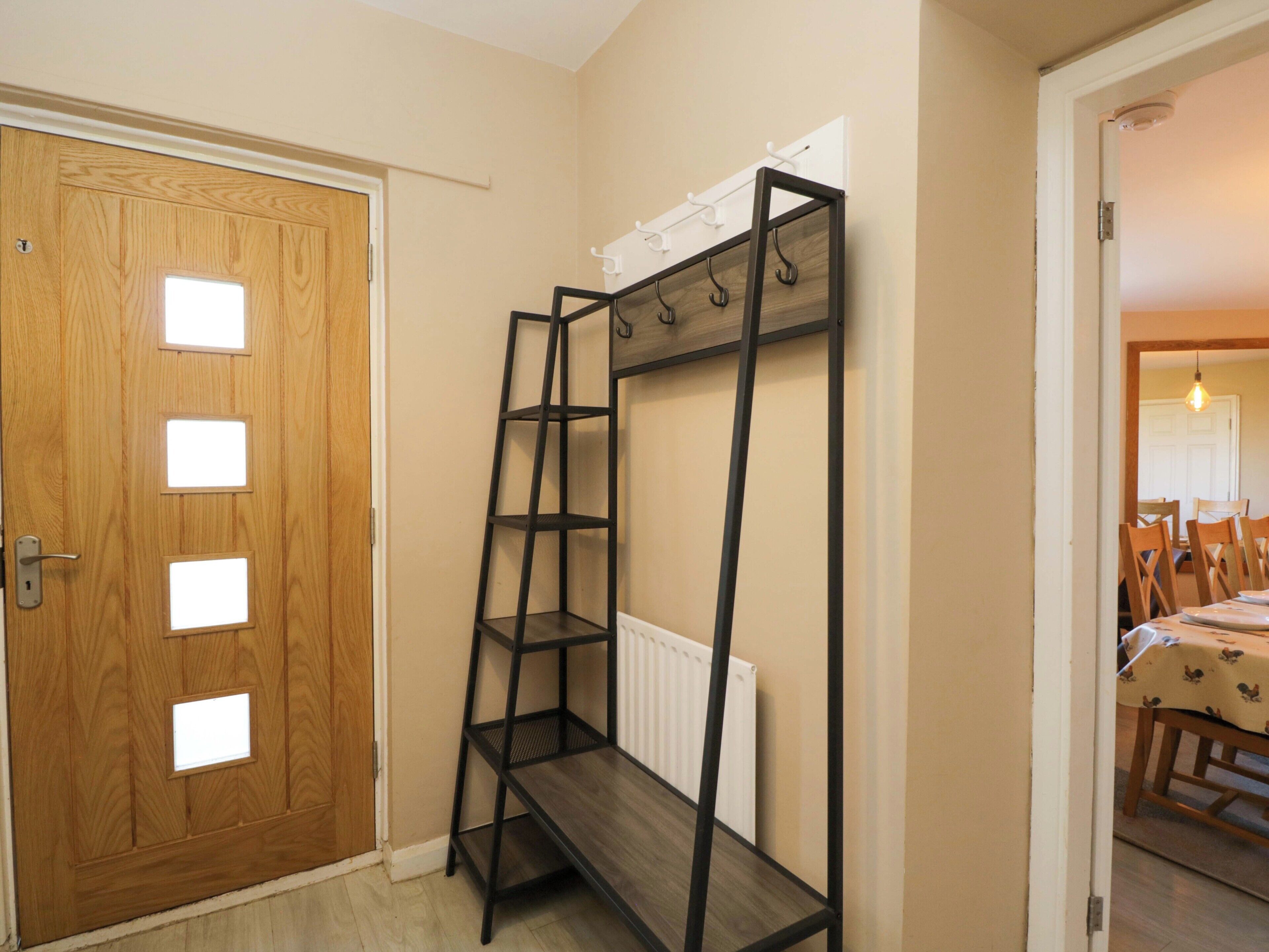 A room with a wooden door, a black metal shelf unit with hooks, and a radiator.