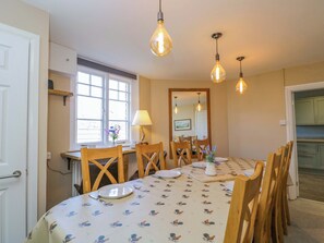 A dining area with a table set for four, wooden chairs, a window with natural light, and hanging light fixtures. - 3 Woods Farm House (Chippenham)