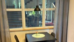 A room with a window, a table with two chairs, a small potted plant, and a lamp. - Söderåsen Airport Hotel (Ljungbyhed)