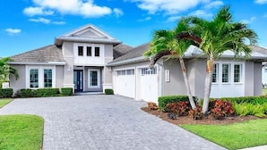 A two-story house with a paved driveway, a front porch, and a well-maintained lawn. - Luxury Naples Retreat / Pool, Near Beach (Naples)