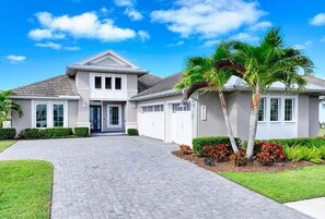 A two-story house with a paved driveway, a front porch, and a well-maintained lawn. - Luxury Naples Retreat / Pool, Near Beach (Naples)