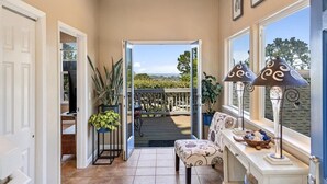 A hallway with a view of a deck, a potted plant, a lamp, and a chair. - 4073 Whale Watcher's Cove - Bay View Home (Monterey)