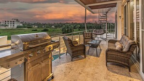 Ein Balkon mit Grill, Korbmöbeln und Blick auf die Landschaft.