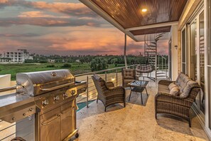 Ein Balkon mit Grill, Korbmöbeln und Blick auf die Landschaft.