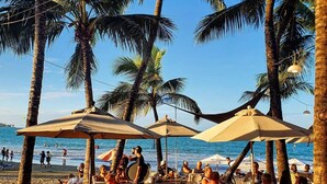 Ein Restaurant direkt am Strand mit Außenbereich, Palmen und Meerblick.