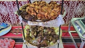 Un bufé con tres niveles de comida, un mantel estampado y vistas al exterior.