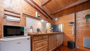 Een houten interieur met een keukenhoek, inclusief een magnetron, fornuis en kasten.