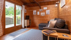 Een houten interieur met een bank, een televisie en ingelijste foto’s aan de muur.
