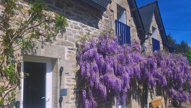 A stone building with a door, windows, and purple flowering vines. - Guesthouse “Lorient Room” with Terrace and Shared Garden (Guilligomarc'h)