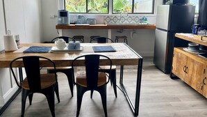 A modern kitchen with a dining area, featuring a wooden table, chairs, a coffee maker, a microwave, and a refrigerator. - Takura Cottage On The Hill with Panoramic Views (Takura)
