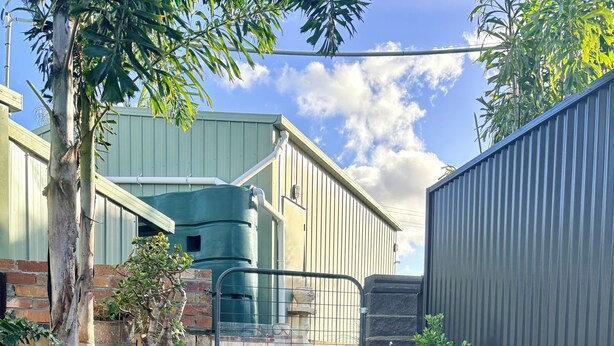 A building with a green roof, a metal fence, and a staircase leading to a gated entrance. - Takura Cottage On The Hill with Panoramic Views (Takura)