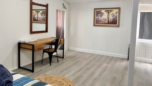 A room with a wooden desk, a chair, a bed with a striped blanket, a woven rug, and two framed paintings on the walls. - Takura Cottage On The Hill with Panoramic Views (Takura)