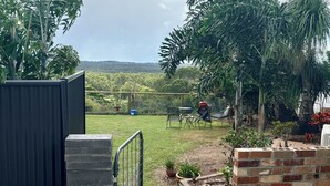 A paved pathway leading to a grassy area with a view of distant hills. - Takura Cottage On The Hill with Panoramic Views (Takura)
