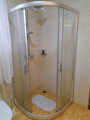 A glass-enclosed shower stall with a handheld showerhead, a soap dispenser, and a drain. - Luxurious 4-bedroom Apartment With Pool Access in Lavington (Nairobi)