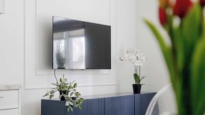 Un saló modern amb televisió de pantalla plana penjada a la paret, un moble armari blau fosc i una planta en test.