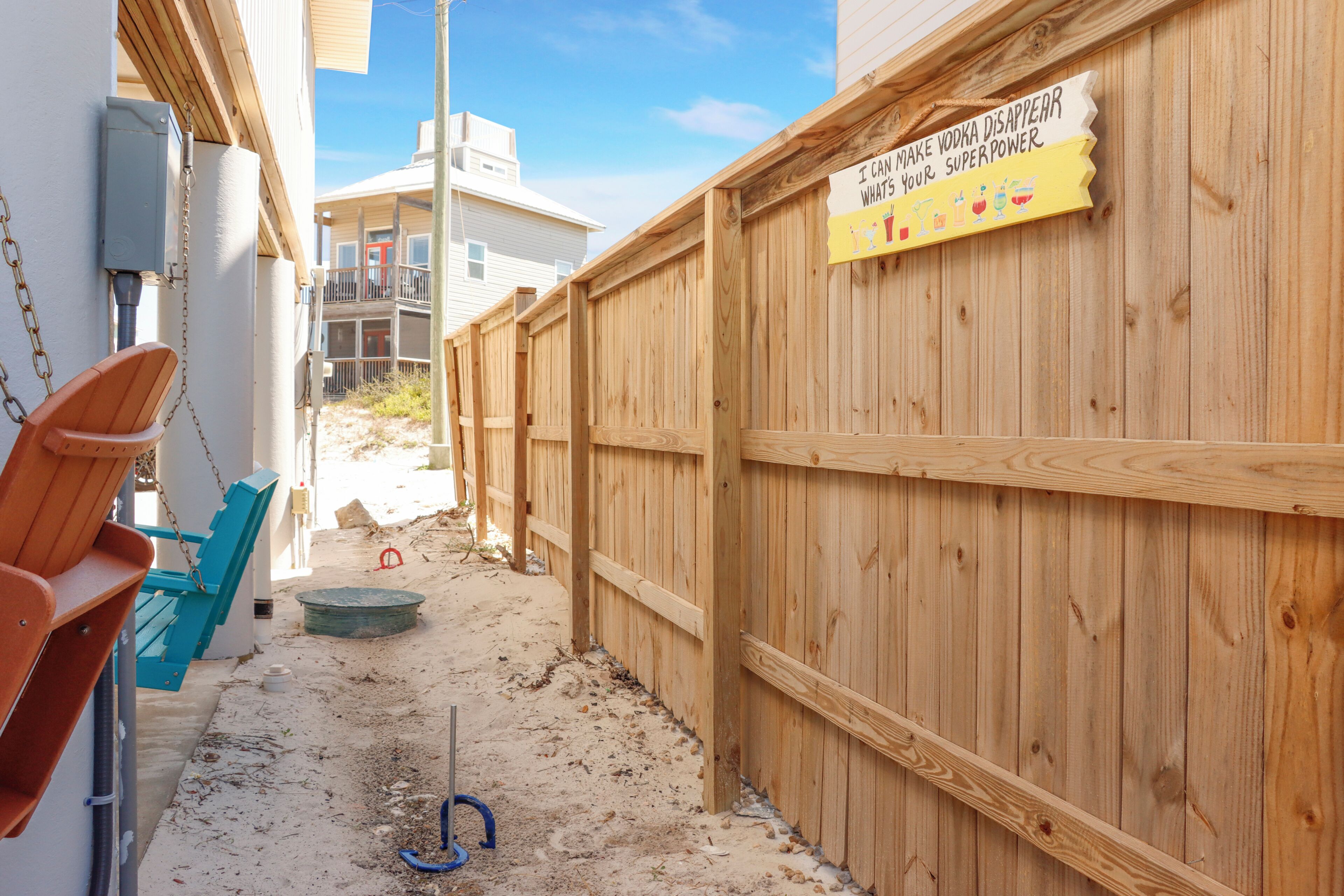 A wooden fence with a sign, a blue chair, and a red chair.