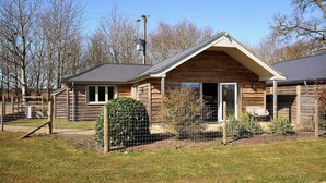 Eine Blockhütte mit Veranda, einem eingezäunten Garten und blauem Himmel.