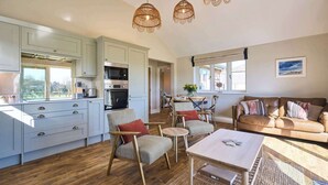 Une cuisine spacieuse équipée d’appareils électroménagers modernes, un coin repas avec des meubles en bois et un salon confortable avec un canapé en cuir.