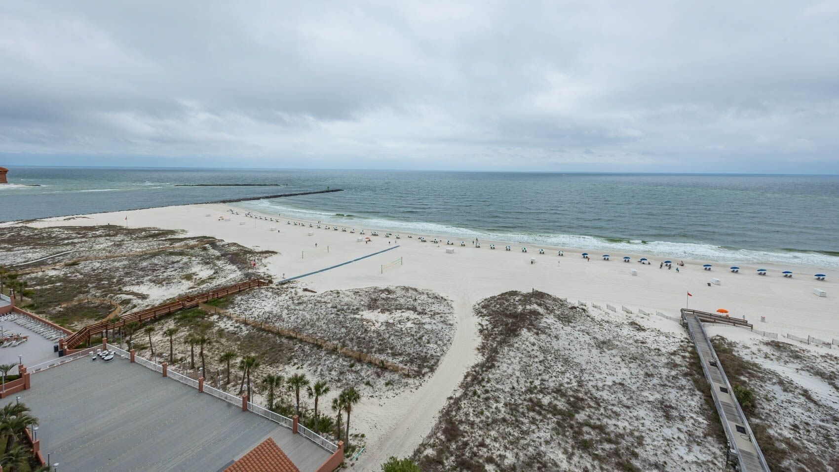 A beach with a sandy shore, a pier, and a building with a roof.