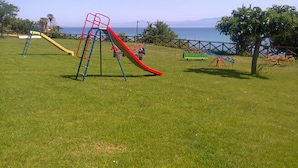 A playground with a red slide, yellow slide, and climbing structures. - FRUIT VILLAGE BAIA DELLA ROCCHETTA (Briatico)