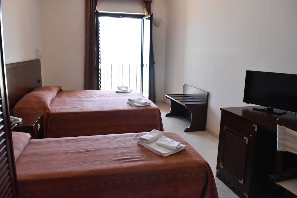 Habitación de hotel con dos camas, televisión, escritorio y ventana.