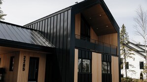 Un bâtiment moderne à l’extérieur noir, agrémenté de touches de bois et doté d’une entrée bien visible, avec une porte portant le numéro « 2285 ».