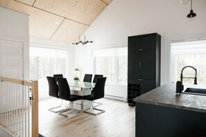 Una cocina moderna con comedor, ventanas amplias y un armario negro.