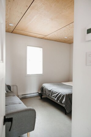 Une chambre avec un lit simple, une fenêtre et un radiateur.
