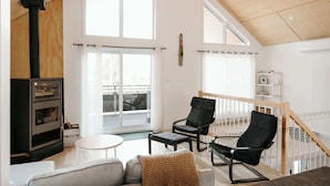 Un vaste espace de vie doté d’une cheminée, de grandes fenêtres et d’un balcon.