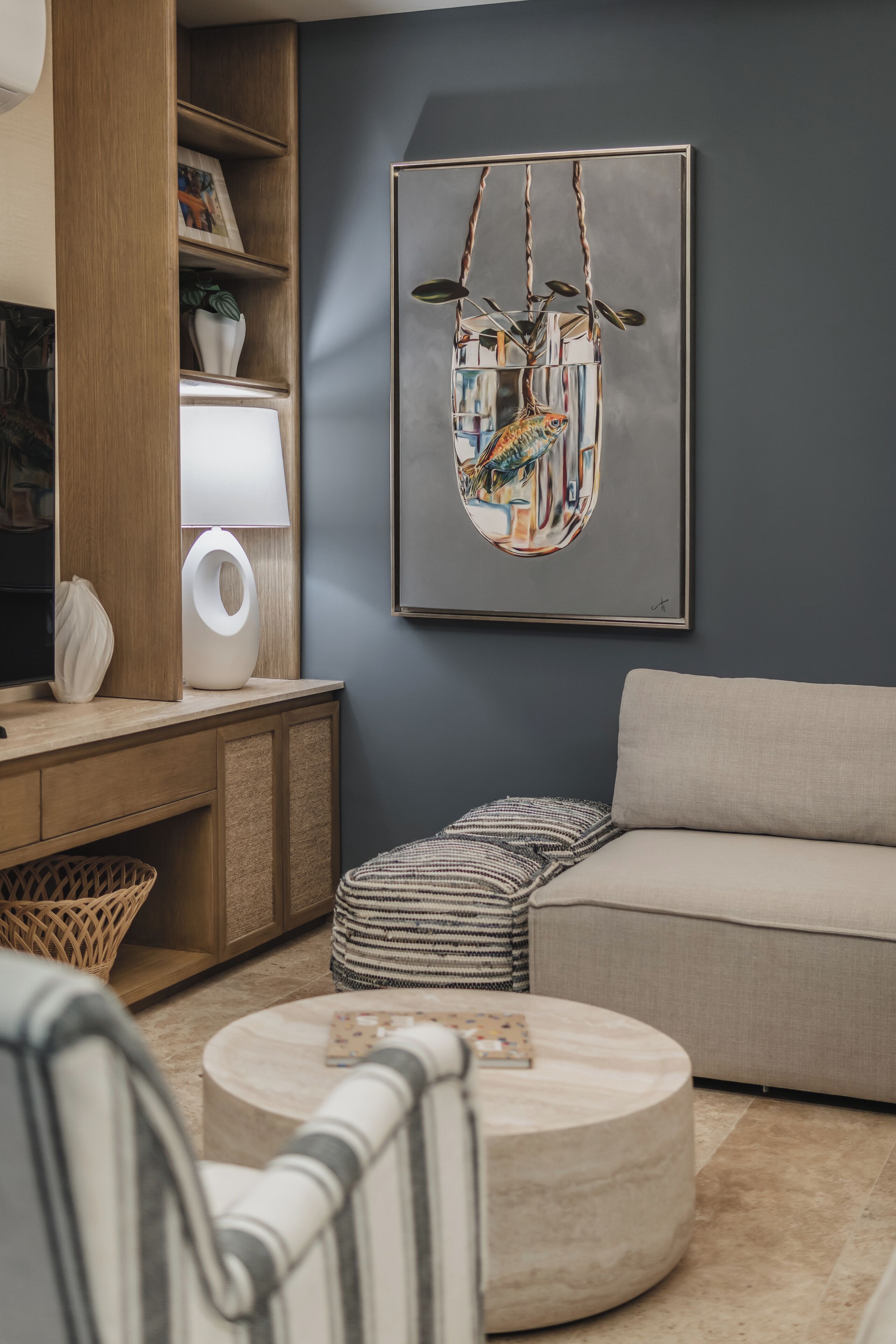 Ein modernes Wohnzimmer mit einer Couch, einem runden Couchtisch, einer Lampe, einem Bücherregal und einem gerahmten Kunstwerk an der Wand.