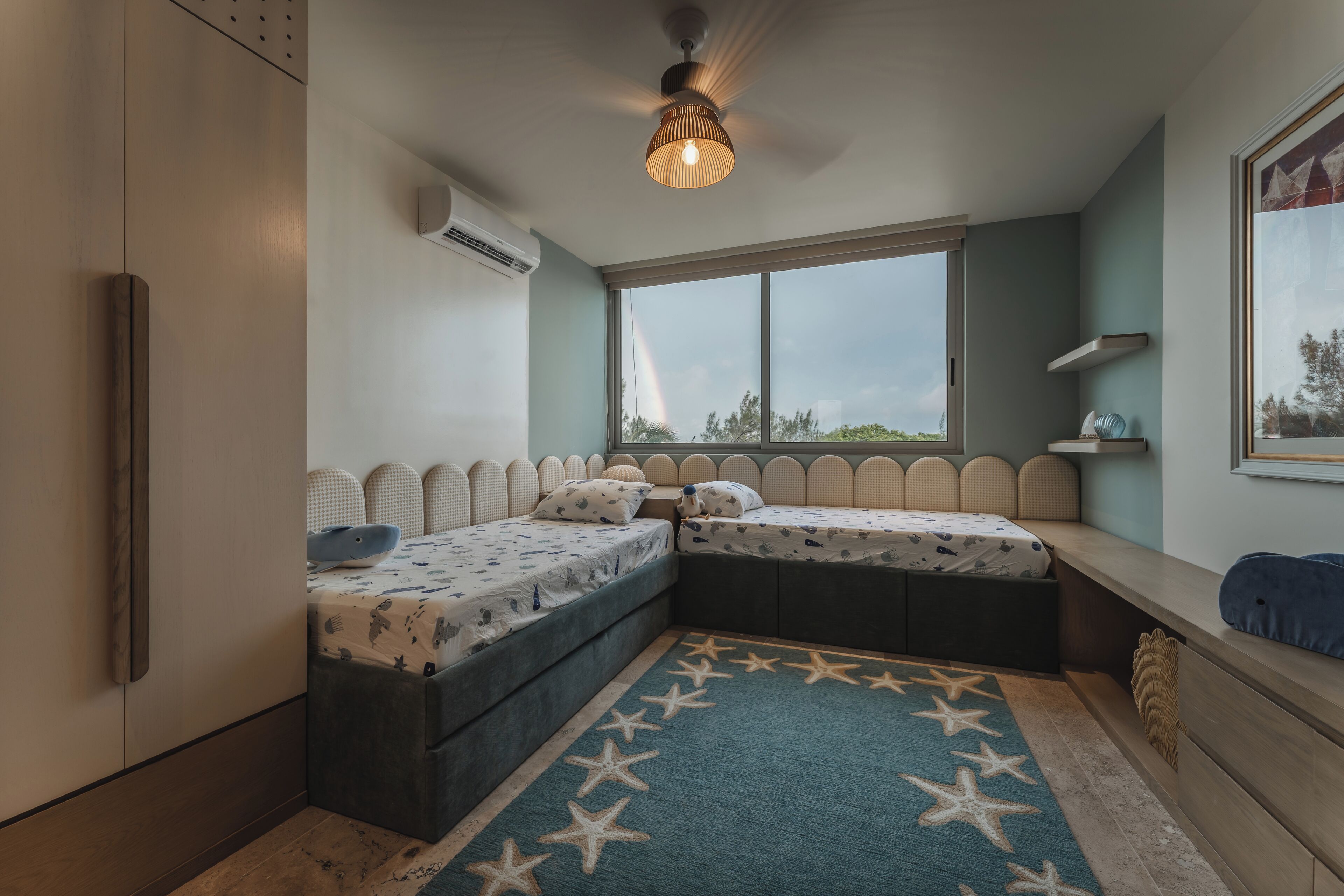 A compact room with a bed, a window, a ceiling light, and a star-patterned rug.