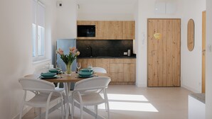 A modern kitchen with wooden cabinets, a black microwave, and a wooden door with a sign. - Apartamenty Sun&Snow Aquamarina Dąbki (Dąbki)