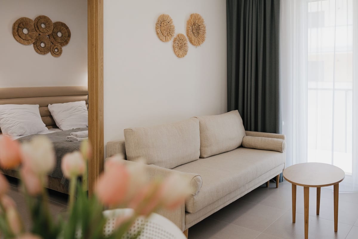 A modern bedroom with a bed, a sofa, a small table, and decorative wall art.