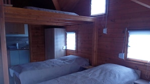 Een blokhut met twee bedden, een kitchenette en een raam.
