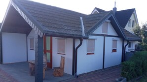 Een tweelaags huis met een overdekte veranda, een schoorsteen en een pad van baksteen dat naar de ingang leidt.