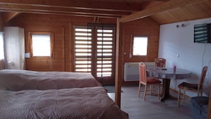 A wooden cabin with two beds, a dining table, and a TV. - Lake pearl at Concordia (Seeland)
