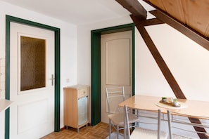 A room with a wooden table, chairs, a cabinet, and a door with a green frame. - Apartment “Linke Hof” with Wi-Fi (Bobritzsch-Hilbersdorf)