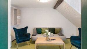 A room with a sofa, two armchairs, a coffee table, and a vase with flowers. - Apartment “Linke Hof” with Wi-Fi (Bobritzsch-Hilbersdorf)
