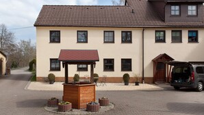 A two-story house with a tiled roof, a wooden gazebo, and a parked van. - Apartment “Linke Hof” with Wi-Fi (Bobritzsch-Hilbersdorf)