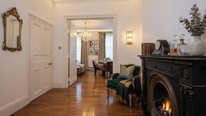 A room with a fireplace, a dining area, and a hallway leading to another room. - Marylebone High Ceiling Private Spacious W1 Home - Luxurylondonstays (London)
