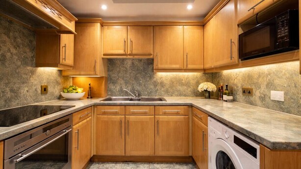 A modern kitchen with wooden cabinets, a built-in oven, a dishwasher, and a microwave. - Marylebone High Ceiling Private Spacious W1 Home - Luxurylondonstays (London)