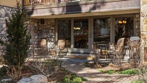 A stone building with a balcony, outdoor seating, and a stone pathway. - Cozy Mountain Getaway by InvitedHome | Walk to Ski, Hot Tub, Village Center (Vail)