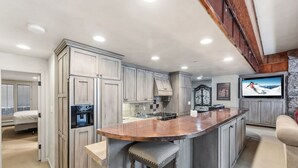 A kitchen with a large island, built-in cabinets, and a stone accent wall. - Cozy Mountain Getaway by InvitedHome | Walk to Ski, Hot Tub, Village Center (Vail)
