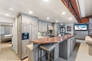 Una cocina con una isla grande, armarios integrados y una pared decorativa de piedra.