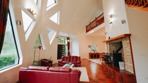 Amplia sala de estar con sofá de cuero rojo, chimenea y un techo alto con tragaluces.