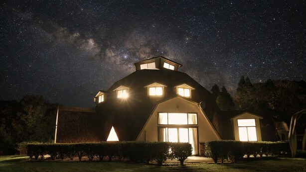 Una casa con techo inclinado, varias ventanas y una entrada principal bien iluminada.