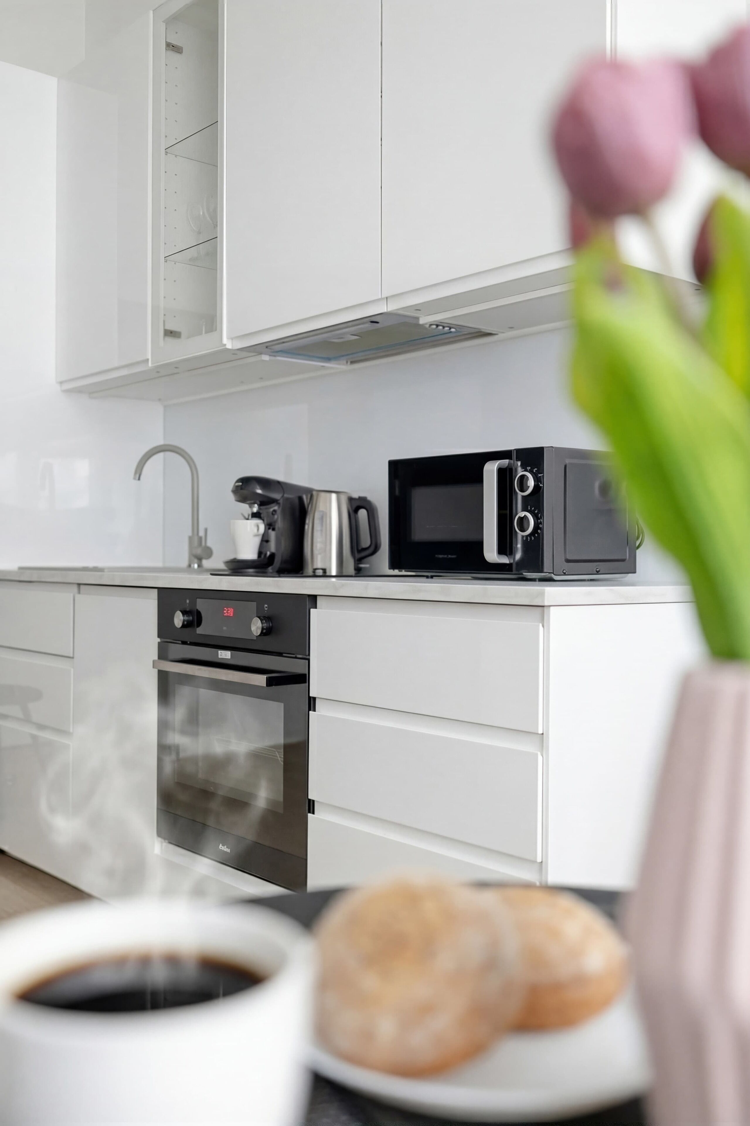 A modern kitchen with a coffee maker, microwave, and oven.
