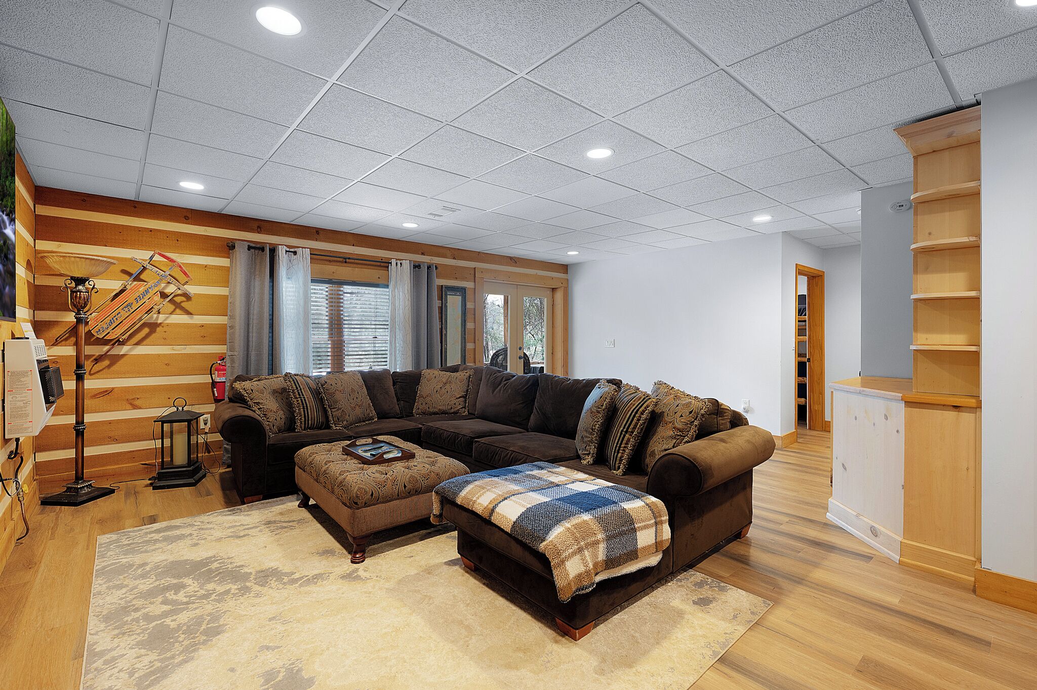 Un salón con un sofá modular, un reposapiés y un mueble de madera.